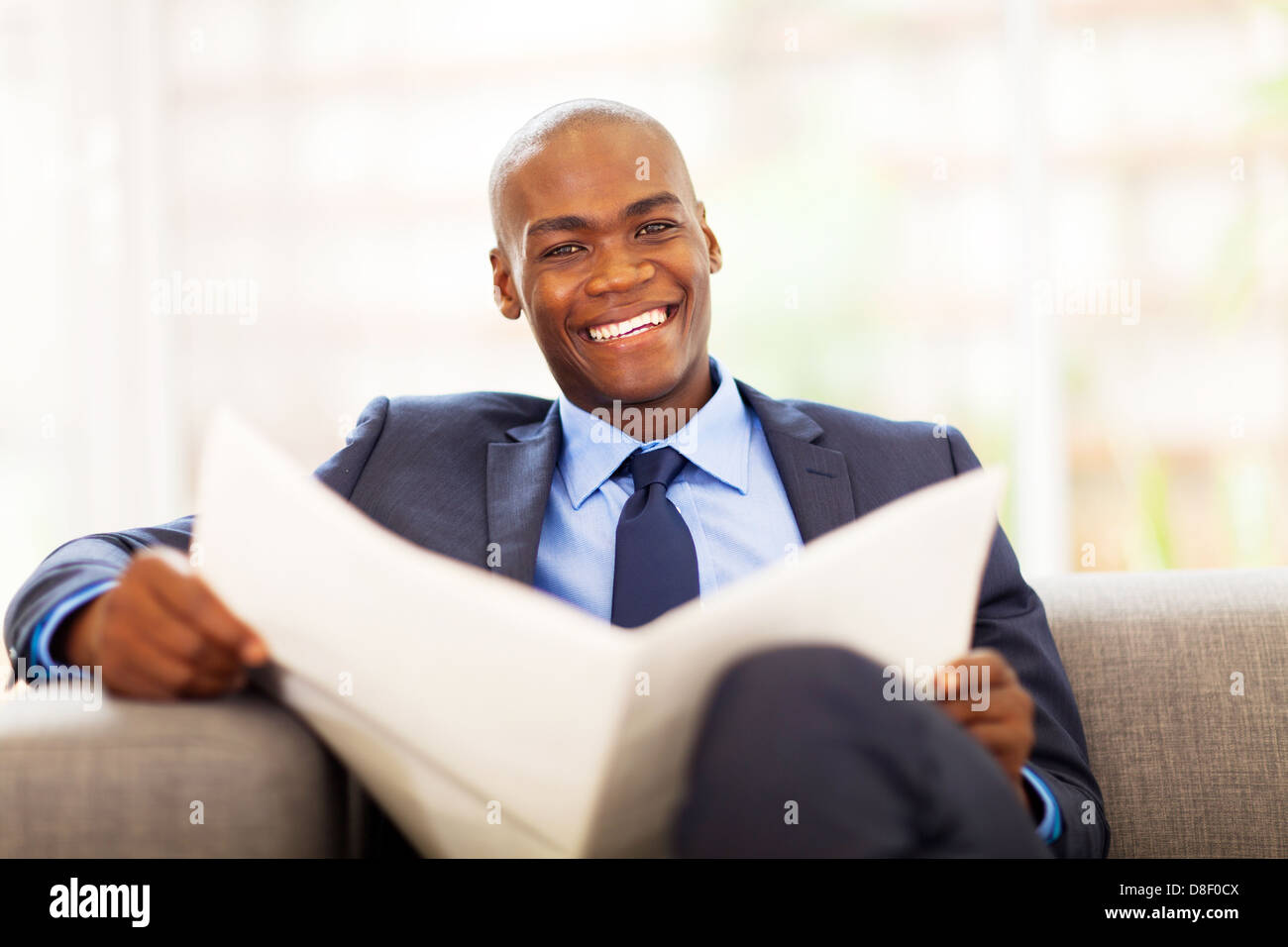 African American imprenditore quotidiano di lettura sul divano Foto Stock