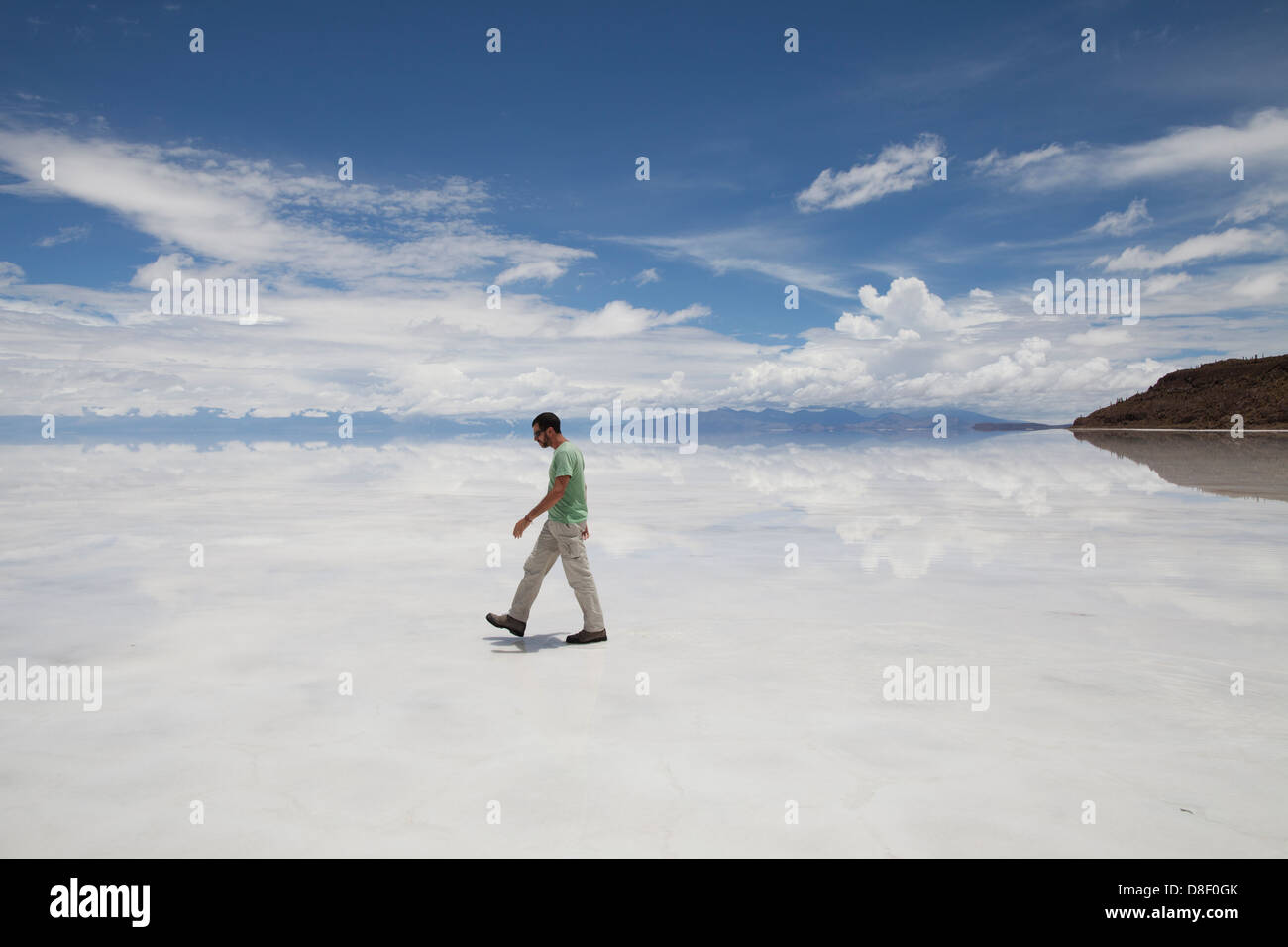 Un uomo in piedi nel tetro bianco paesaggio - Salar de Uyuni in Bolivia Foto Stock