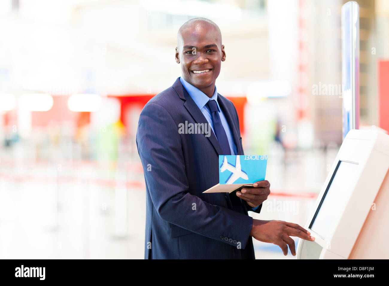 Imprenditore africano usando self service check in macchina in aeroporto Foto Stock