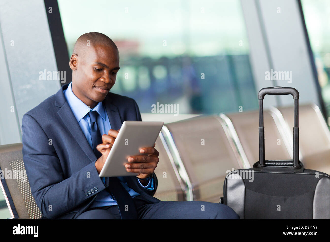 Imprenditore nero utilizzando computer tablet all aeroporto Foto Stock