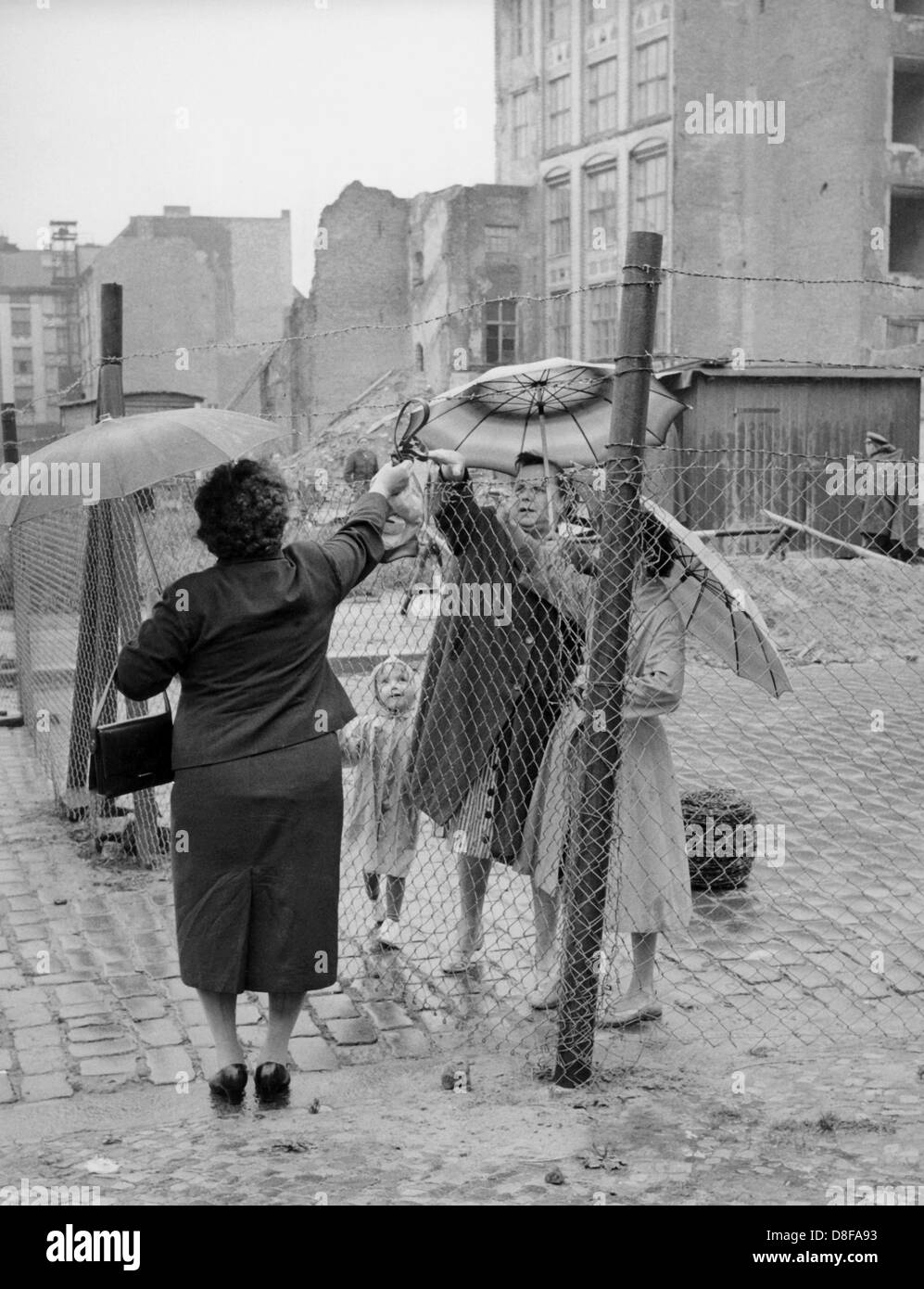 Eine Frau aus Westberlin (l) reicht ein Päckchen über den Zaun an der Sektorengrenze Chauseestraße/Boysenstraße a Berlino. In der Nacht zum 16.08.1961 wurde an der Stelle ein fast zwie Meter hoher Maschendrahtzaun errichtet. Am frühen Sonntagmorgen des 13. Agosto 1961 wurde unter der Aufsicht von bewaffneten Streitkräften der DDR mit der Errichtung von Straßensperren Stacheldraht aus dem und Bau einer Mauer begonnen, um den Ostteil berlinese Westteil vom abzusperren. Die Mauer sollte den ständig steigenden Flüchtlingsstrom von Ost- nach Berlino Ovest stoppen. Foto: Günter Bratke +++(c) dpa - Repor Foto Stock