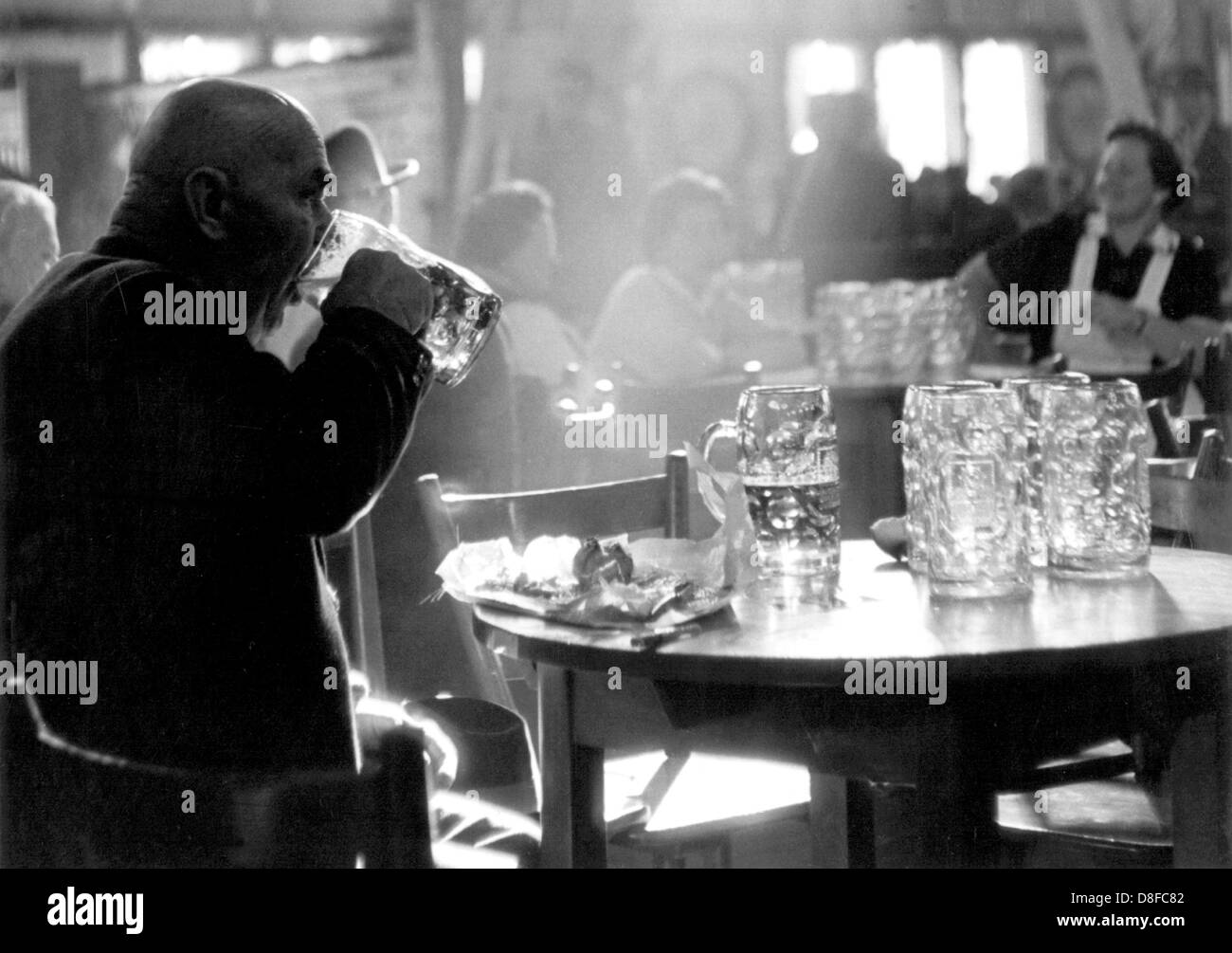 Un uomo da Monaco di Baviera si gode la sua birra in un bar bavarese, fotografato il 2 marzo nel 1964. Foto Stock
