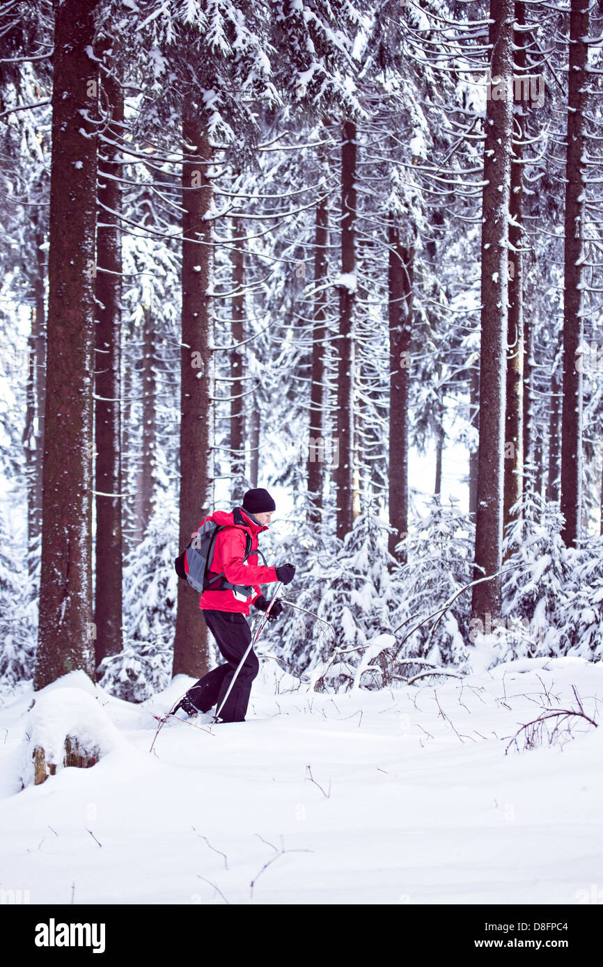 Donna passeggiate con le racchette da neve in una foresta di inverno Foto Stock