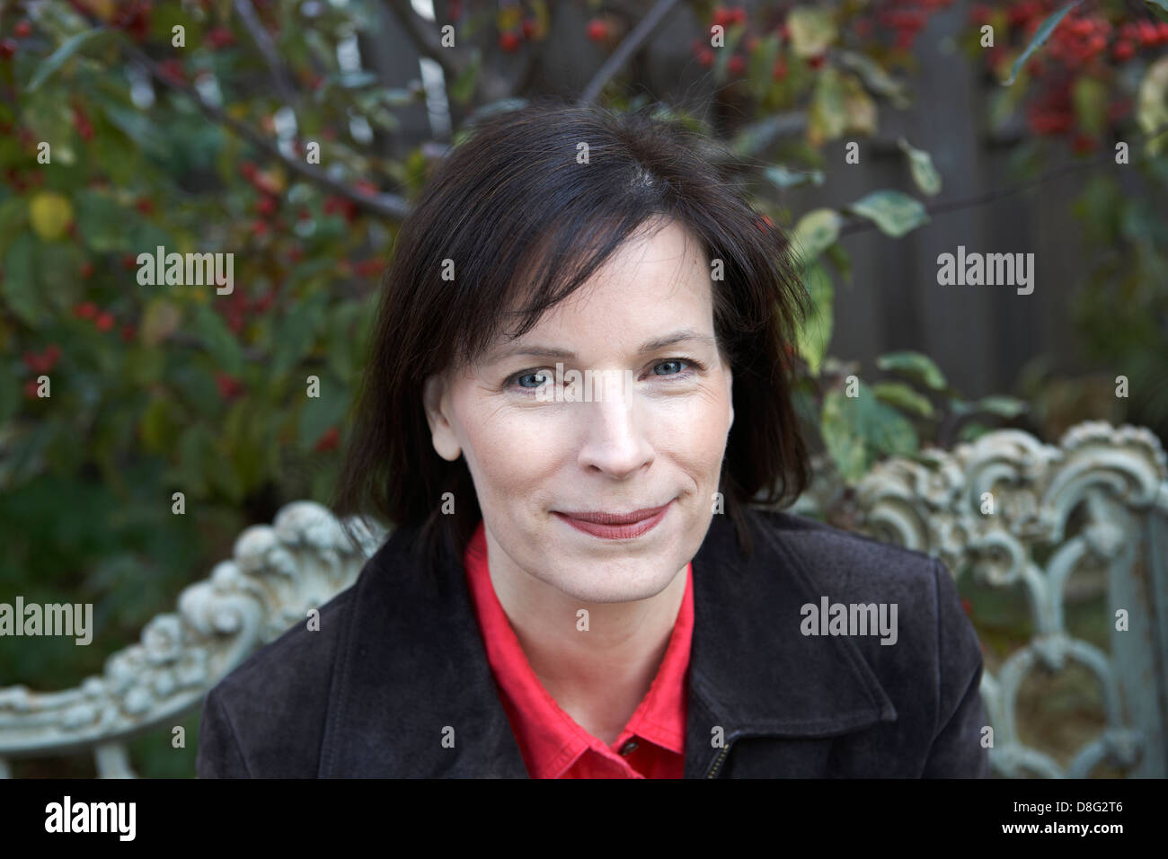 Donna di mezza età seduta sulla panchina da giardino Foto Stock