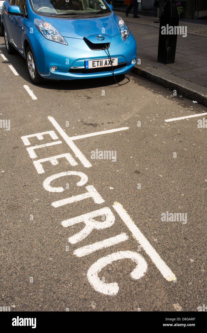 Una Nissan Leaf, un auto elettrica in corrispondenza di una pavimentazione con stazione di ricarica in Londra. Foto Stock