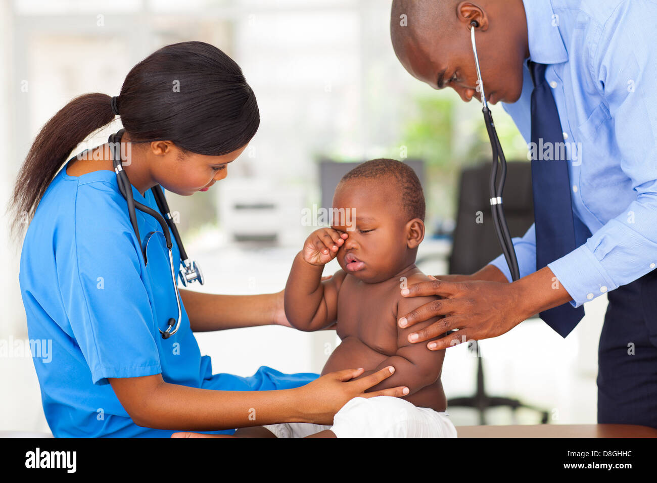 Afro American pediatra maschio e femmina infermiera esaminando un bimbo in clinica Foto Stock