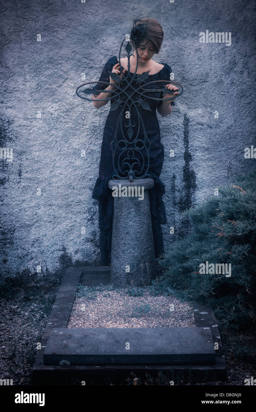 Un dolore di donna con velo e abito scuro su un cimitero Foto Stock