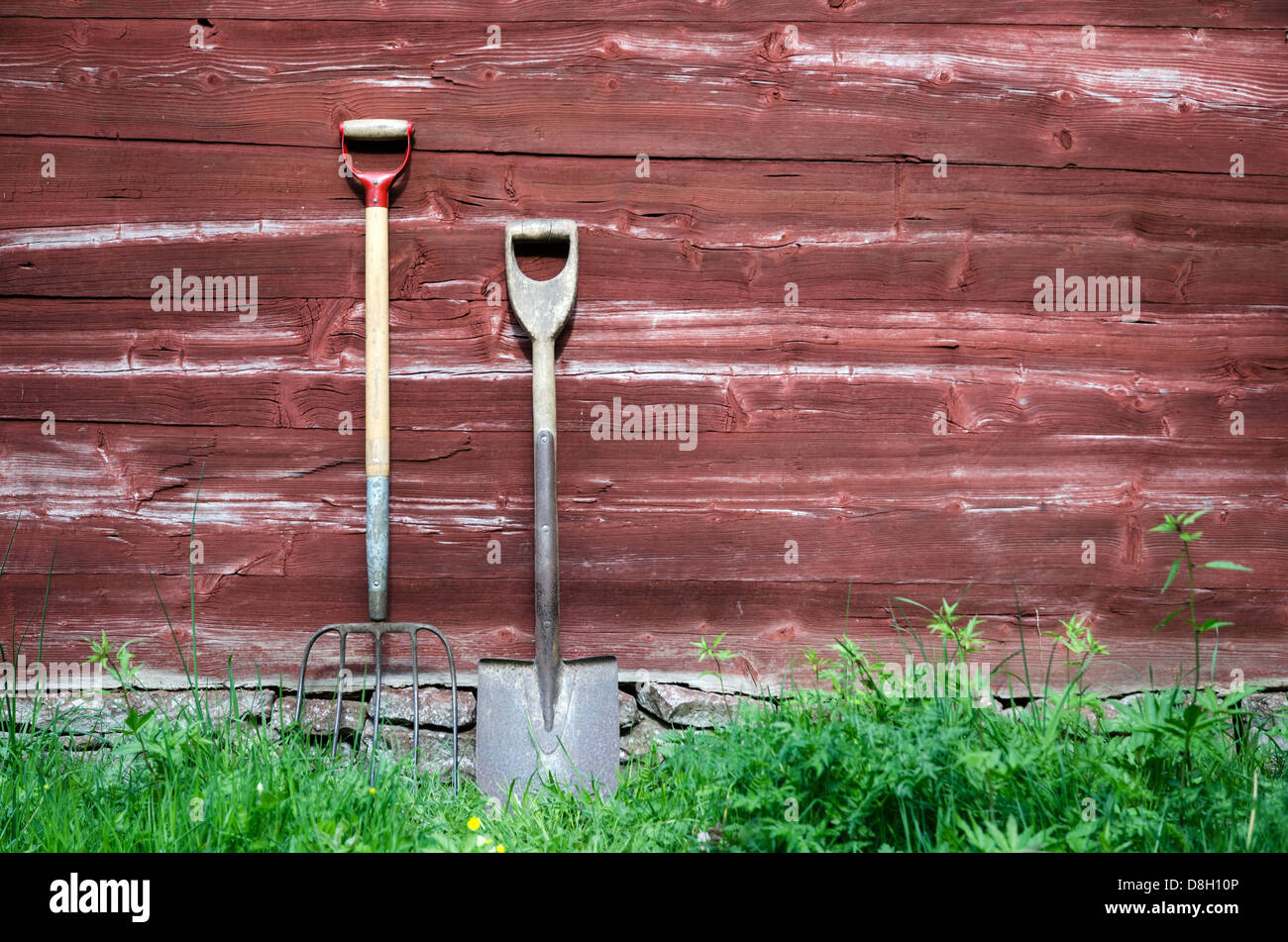 Gli agricoltori vecchi strumenti in piedi in un vecchio fienile spiovente parete. Foto Stock