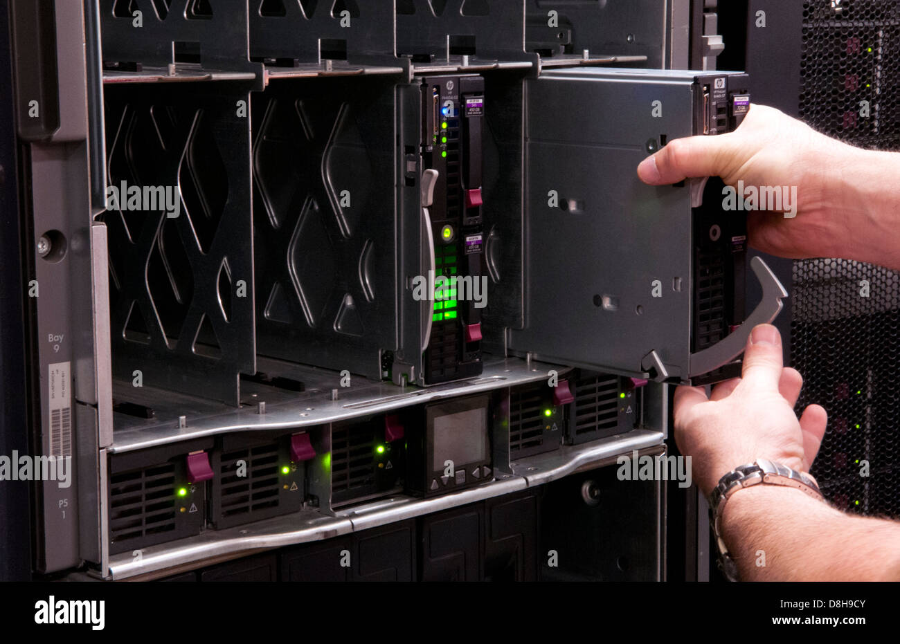 L'uomo l'installazione di lame in grandi impilate computer server nel gruppo IT industry Foto Stock