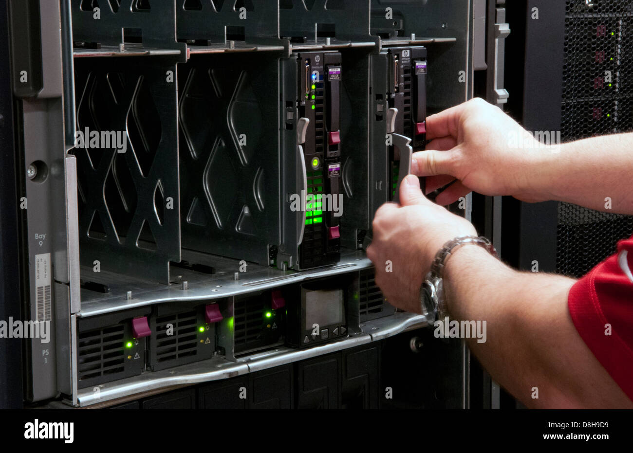 L'uomo l'installazione di lame in grandi impilate computer server nel gruppo IT industry Foto Stock