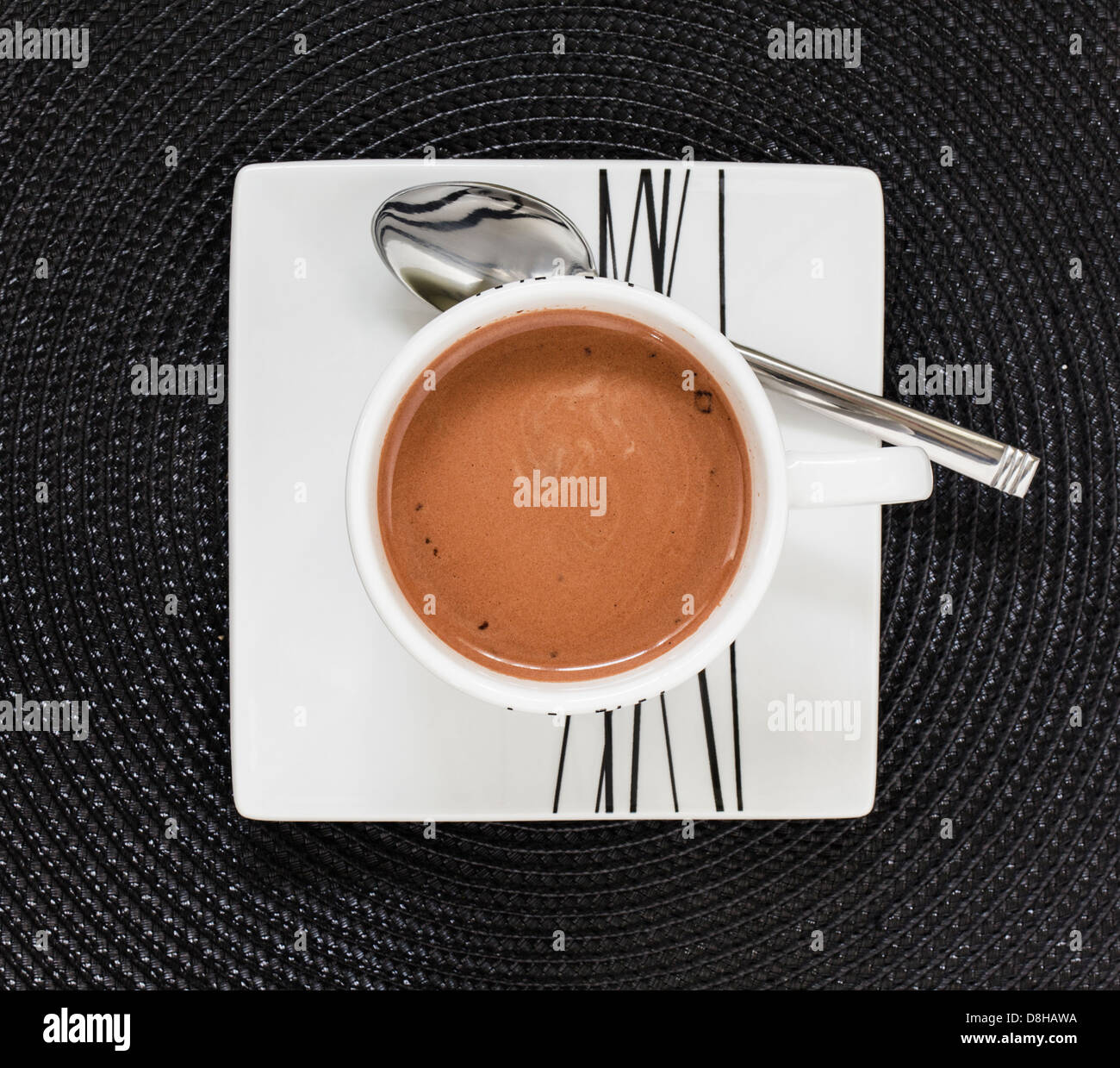 Cioccolata calda bevanda nella tazza bianca e il piattino su nero tablemat Foto Stock