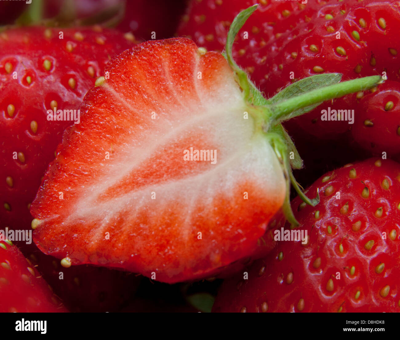 Fragole britanniche così brillante frutta rossa d'estate! Primo piano di un frutto tagliato a metà, mostrando semi Foto Stock