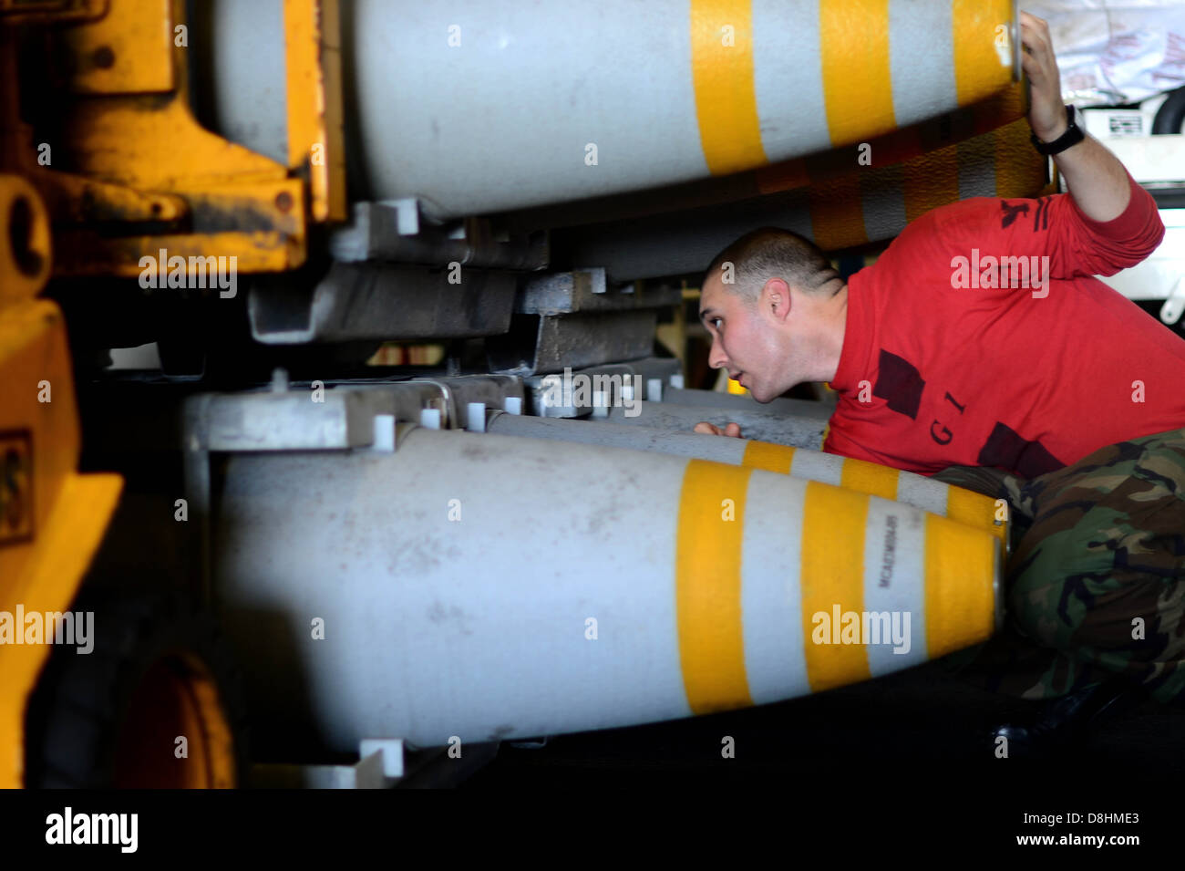 Un marinaio di pile ordnance nell'hangar bay. Foto Stock