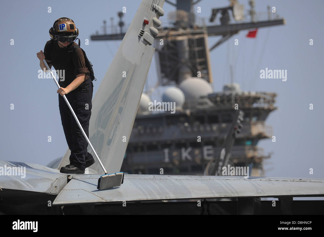 Un marinaio pulisce un F/A-18. Foto Stock