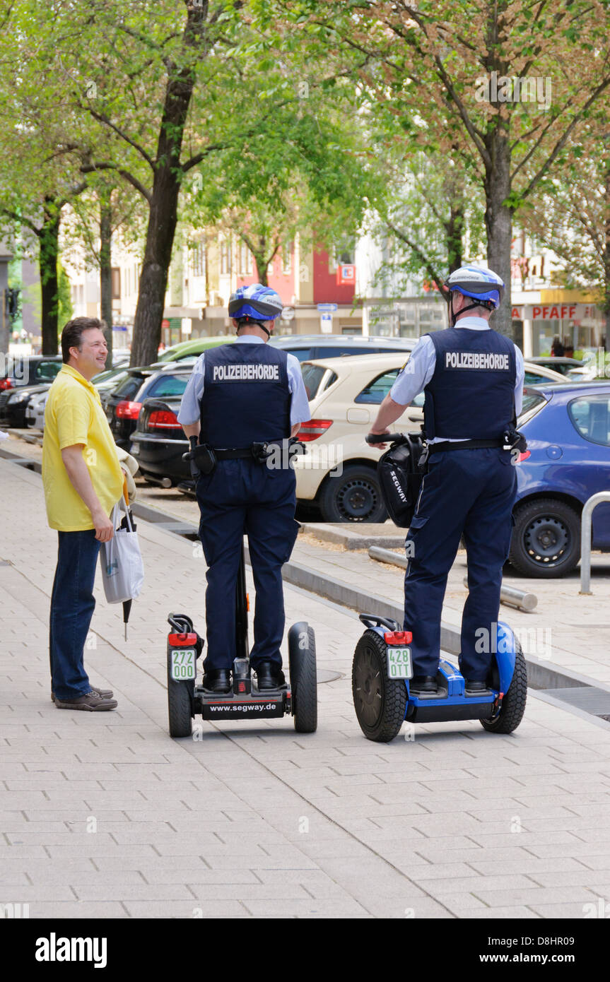 Due poliziotti tedeschi di pattuglia con un Segway personal transporter interagente con un uomo in pubblico - Heilbronn Germania Foto Stock