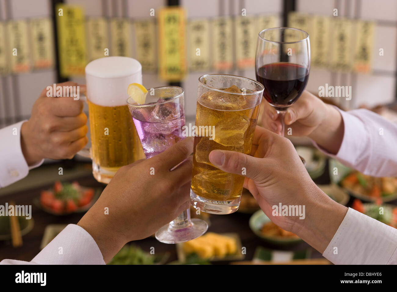 Quattro persone la tostatura gli uni con gli altri con varie bevande a Izakaya Foto Stock