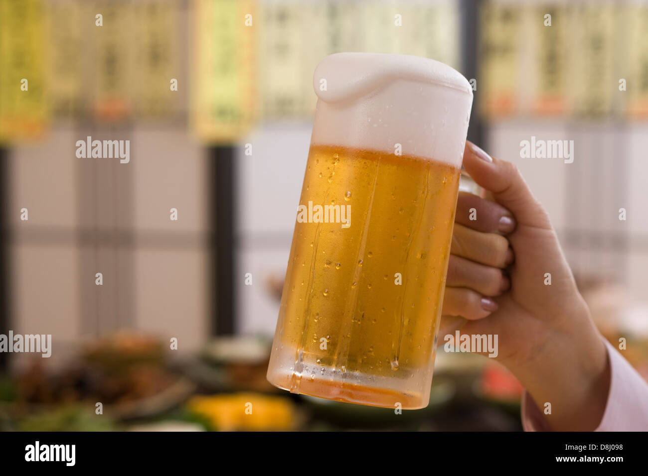Mano umana azienda boccale di birra a Izakaya Foto Stock