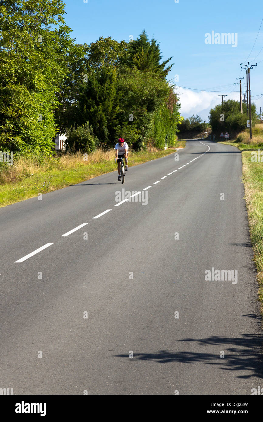 Lone ciclista su strada di campagna, Charentes Maritime, Francia Foto Stock