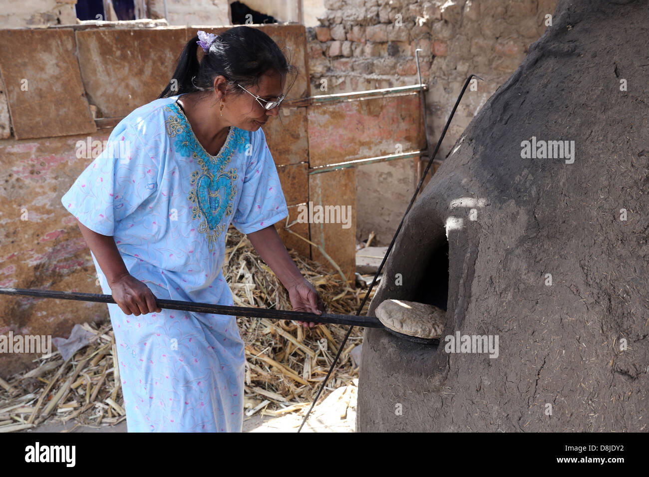 Donna egiziana rendendo il pane piatto in un forno di pietra, Alto Egitto Foto Stock