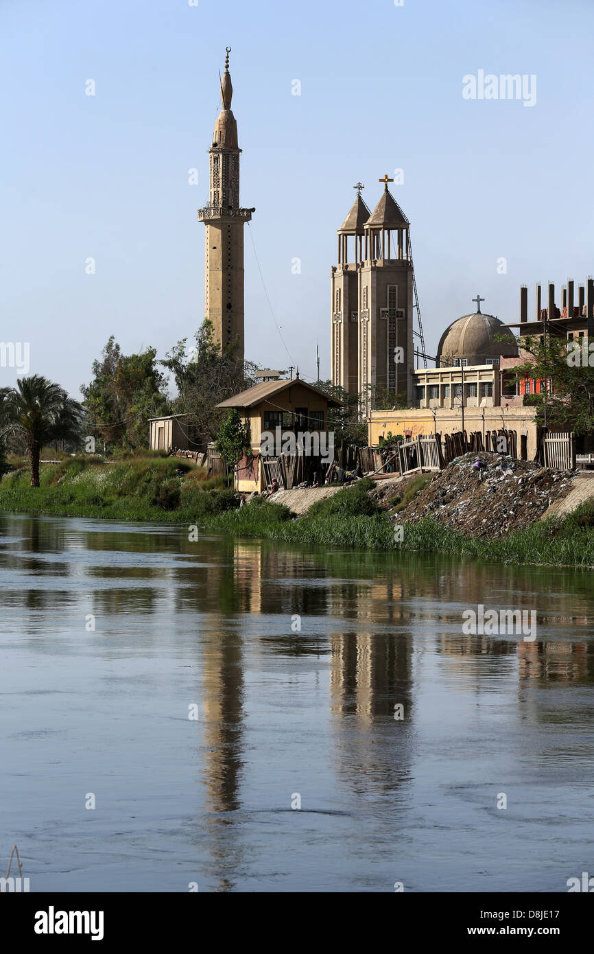 Una croce cristiana su una chiesa copta e cresent sul minareto della moschea musulmana in Alto Egitto Foto Stock