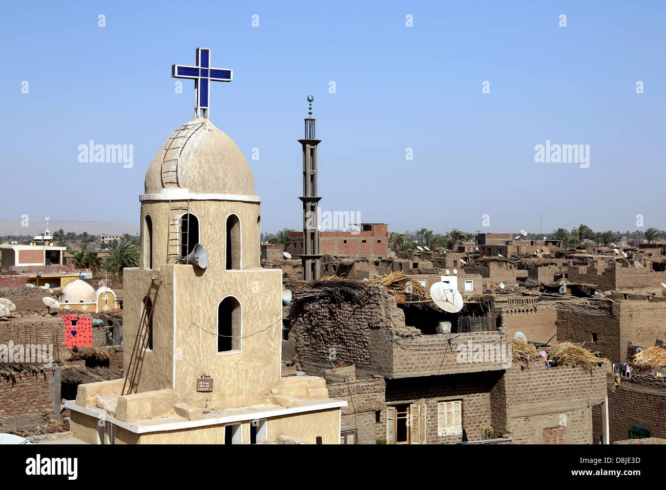 Una croce cristiana su una chiesa copta e cresent sul minareto della moschea musulmana in Alto Egitto Foto Stock