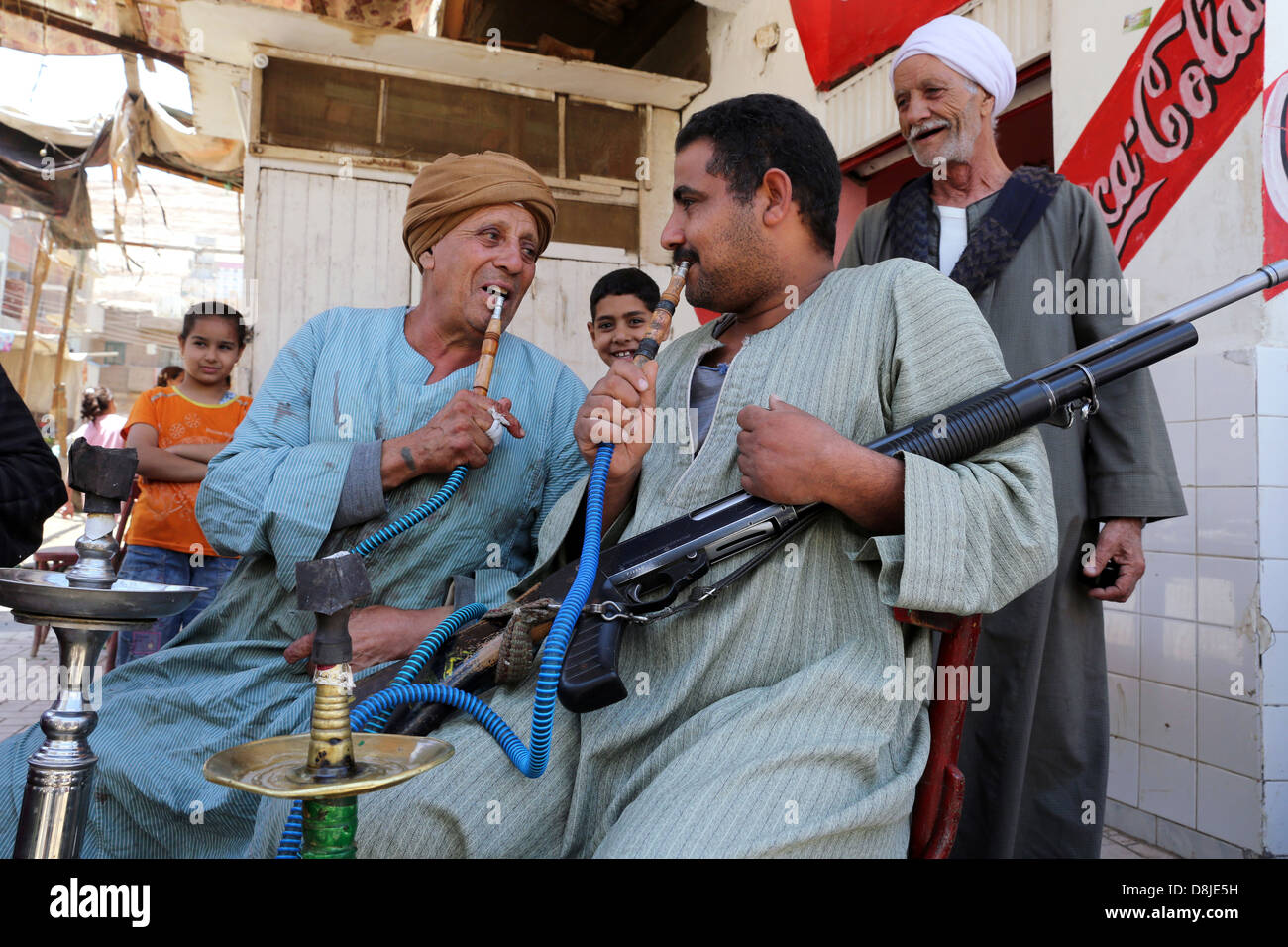 Gli uomini withe un fucile di fumare pipa ad acqua shisha in un bar in un villaggio in Alto Egitto Foto Stock