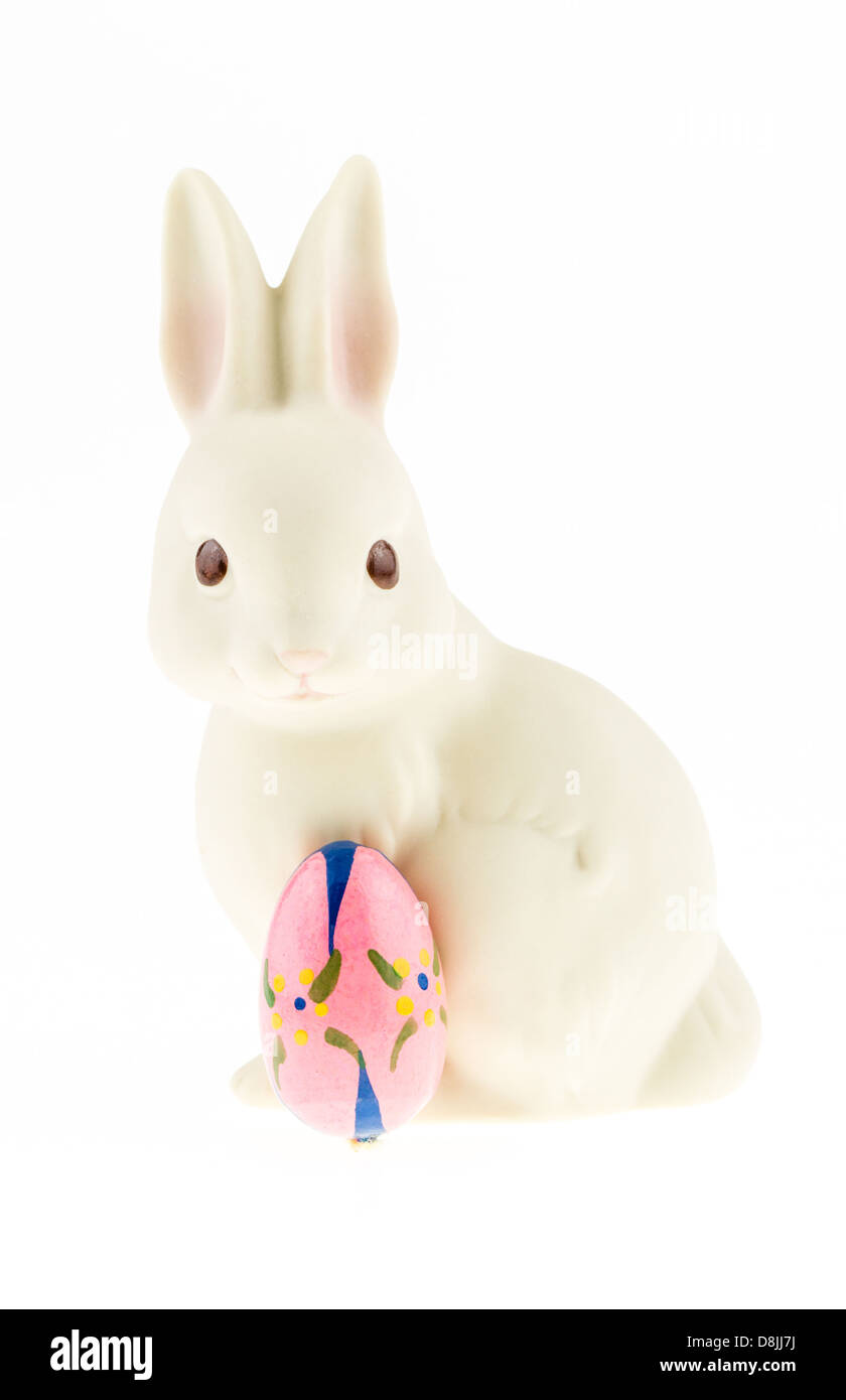 Ceramica coniglietto di Pasqua con un uovo di pasqua isolata contro uno sfondo bianco. Foto Stock
