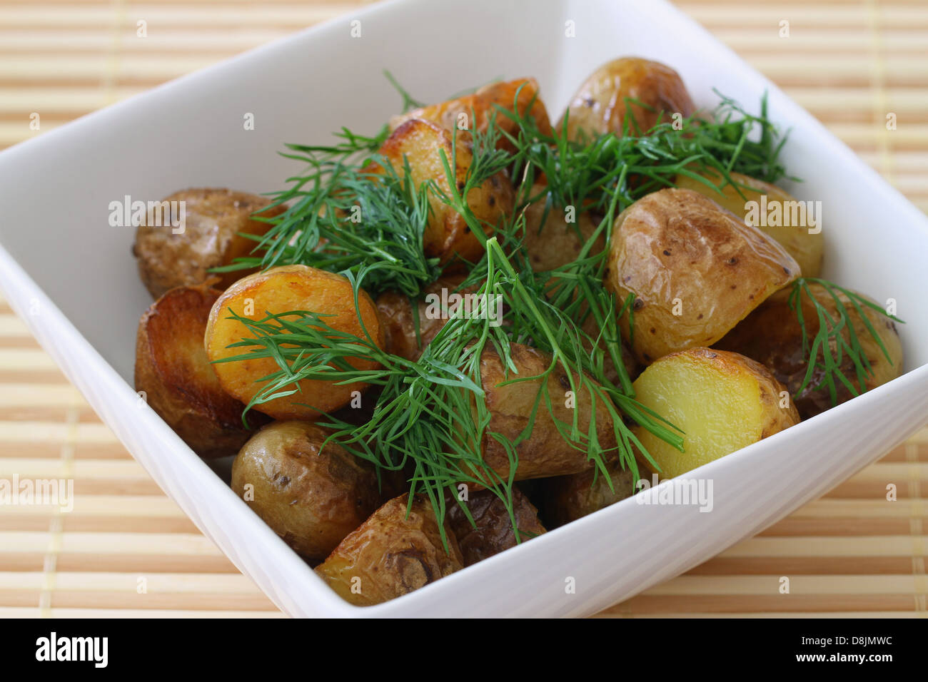 Bambino arrosto patate guarnite con aneto fresco, vicino fino Foto Stock