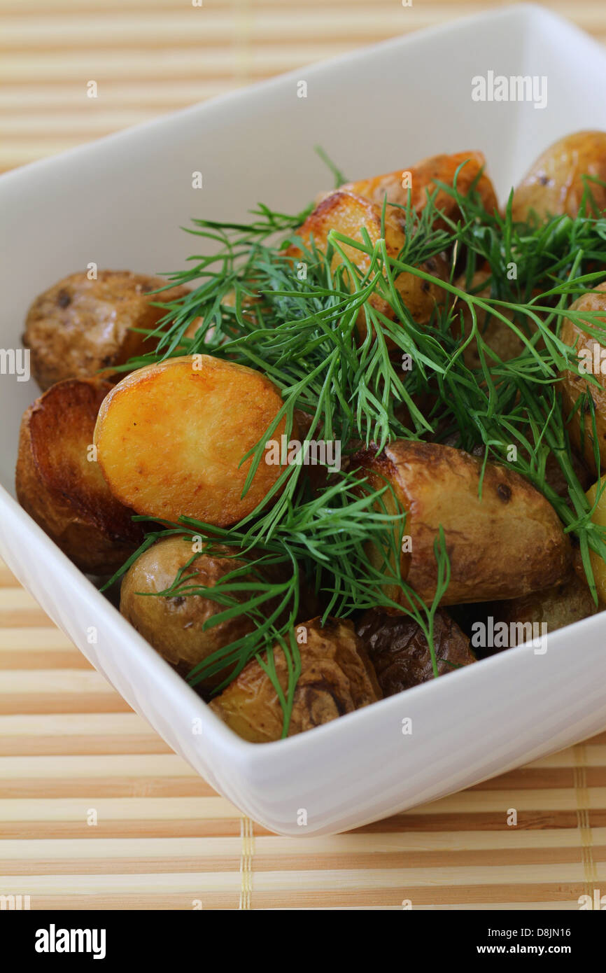 Bambino arrosto patate guarnite con aneto fresco, vicino fino Foto Stock