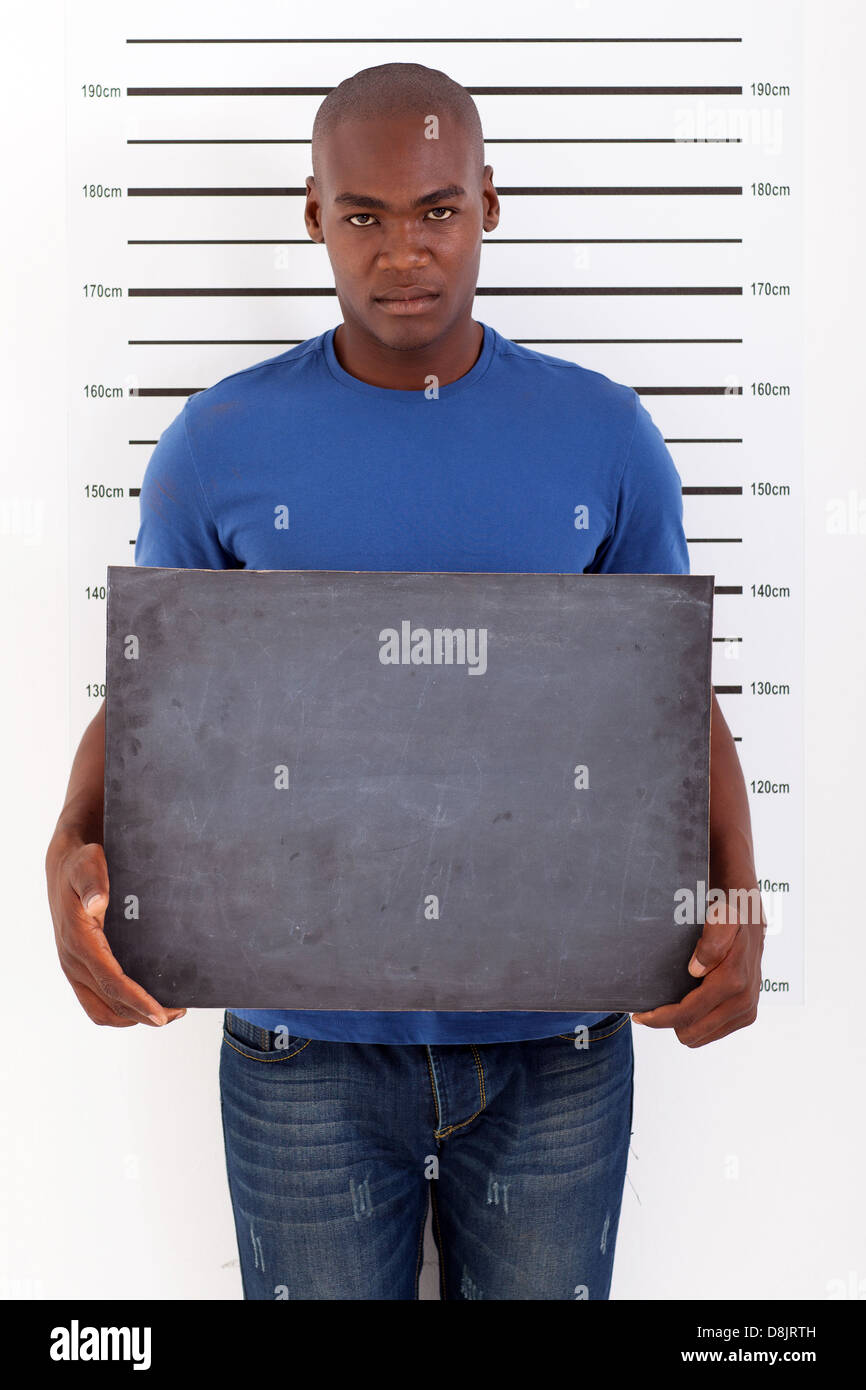 Giovane africano tenendo un bordo nero la polizia mug shot Foto Stock