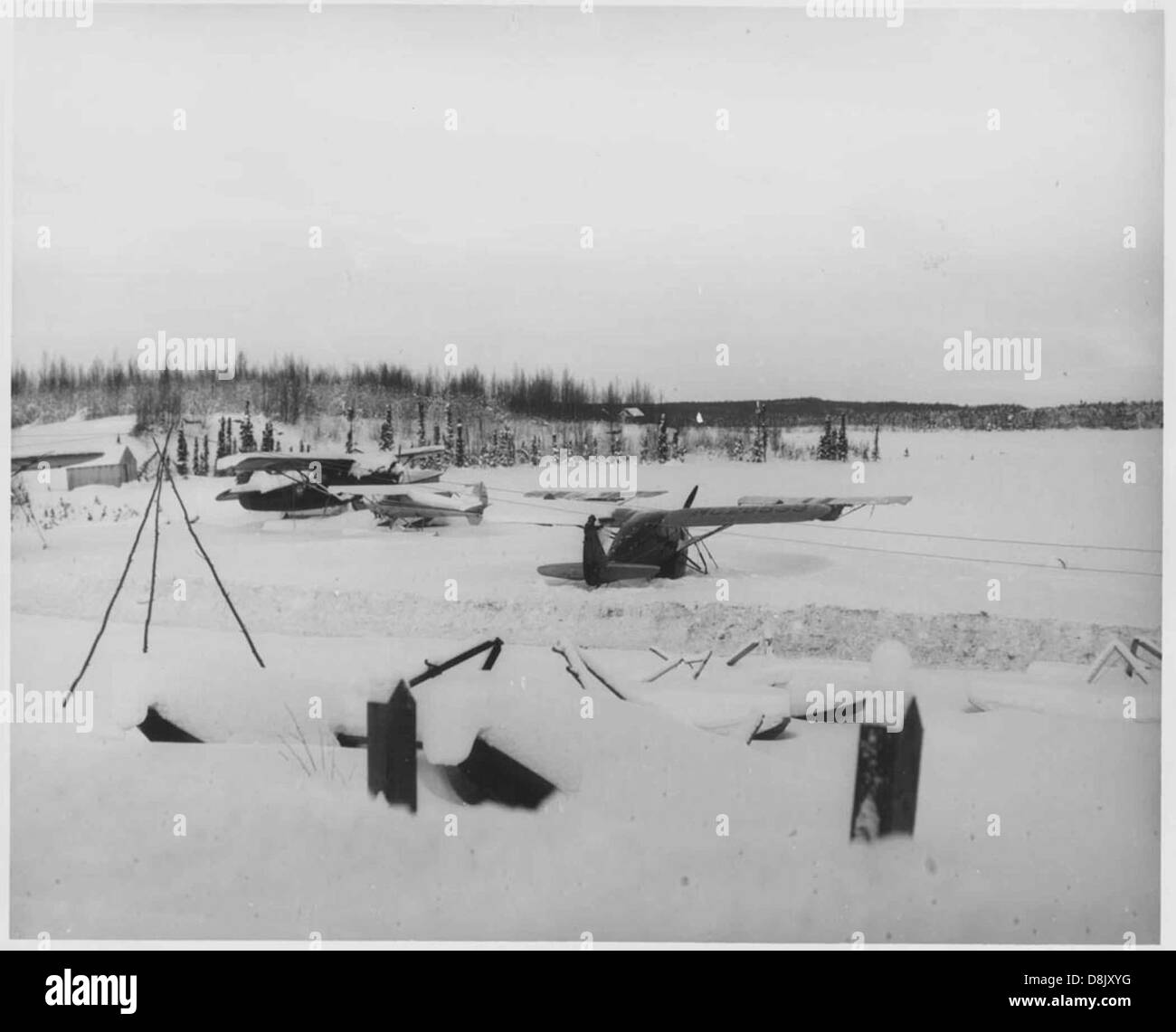 Gli aerei sono visti vicino agli hangar in un ambiente innevato, evidenziando lo stoccaggio e la manutenzione degli aeromobili in condizioni fredde. Le condizioni nevose possono mettere in discussione l'aviazione, ma sono spesso gestite con attrezzature e infrastrutture specializzate. Foto Stock