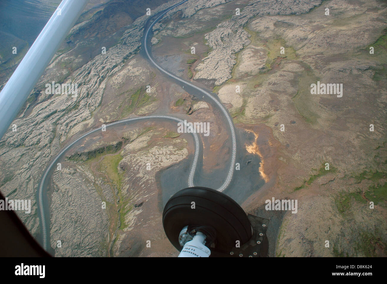 Una strada i serpenti attraverso campi di lava e oro acqua riflettente visto da di sightseeing volo sopra il sud dell'Islanda in velivoli leggeri Foto Stock
