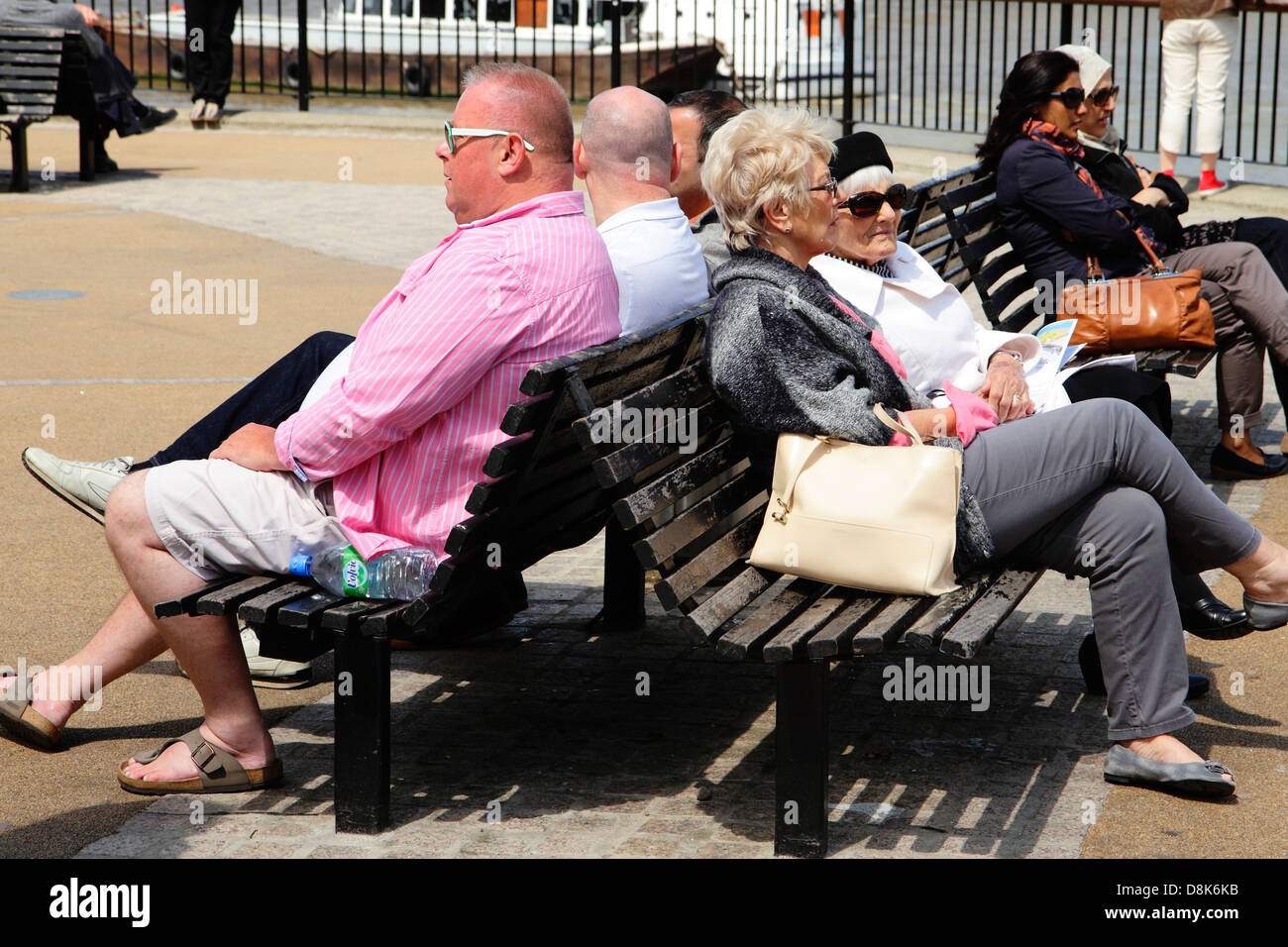 La gente seduta sulle panchine pubbliche in sun. Bankside, London, Regno Unito Foto Stock