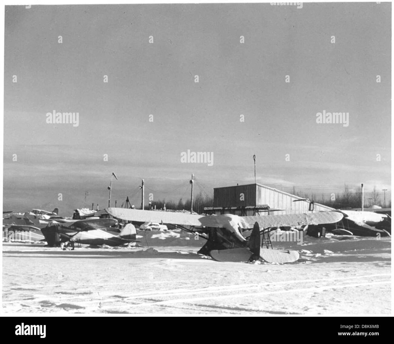 I piccoli aeroplani sono parcheggiati in un aeroporto durante la stagione invernale, circondati dalla neve. Il freddo mette in evidenza le sfide dell'aviazione durante i mesi invernali, con piste e aerei innevati. Foto Stock