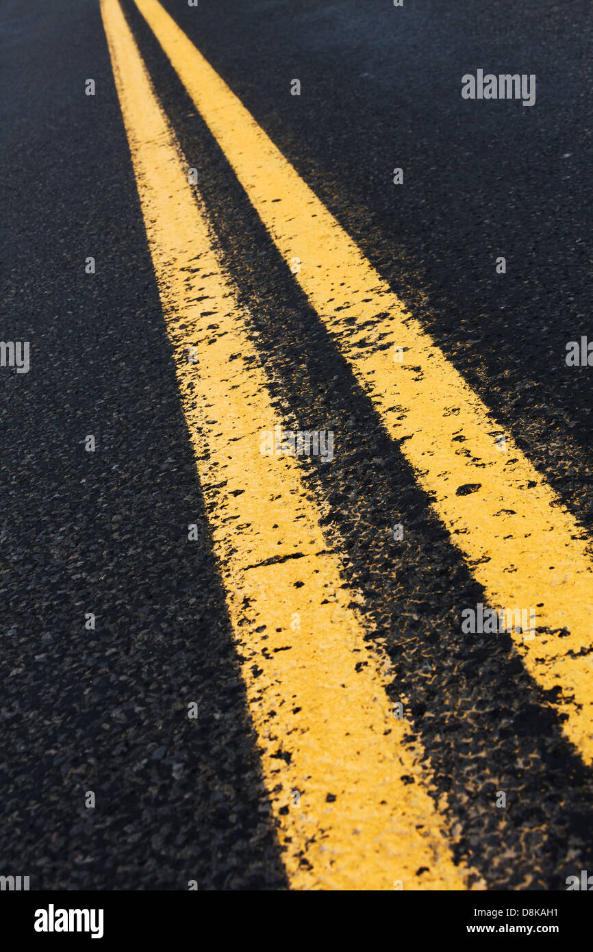 Doppia linea gialla e la strada asfaltata per lo sfondo Foto Stock