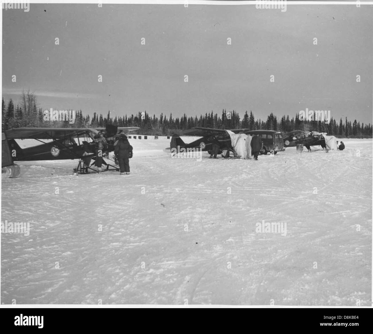 Gli idrovolanti sono parcheggiati su un campo d'aviazione innevato, con aerei personali visibili sullo sfondo. L'ambiente freddo e innevato contrasta con i velivoli funzionali, pronti per il volo. Foto Stock