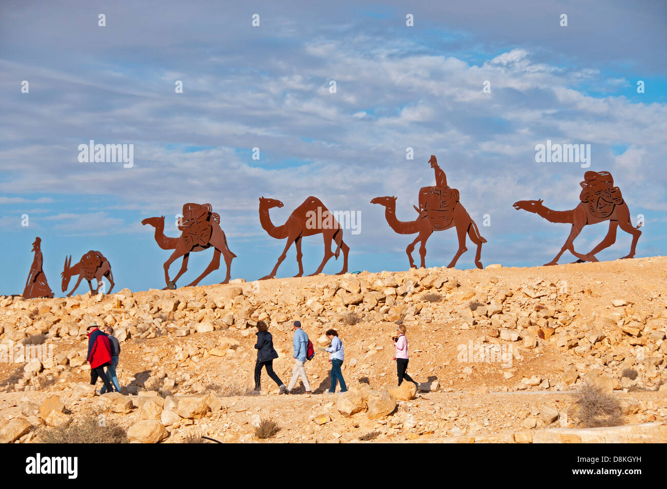 Un gruppo di turisti a piedi sul sentiero sotto figure di animali che hanno svolto un ruolo nel percorso di incenso a Avdat National Park, Israele Foto Stock
