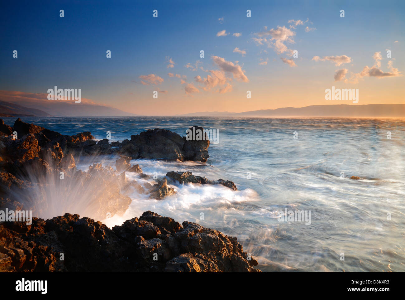 Spruzzi di onde di rocce dal mare al tramonto Foto Stock
