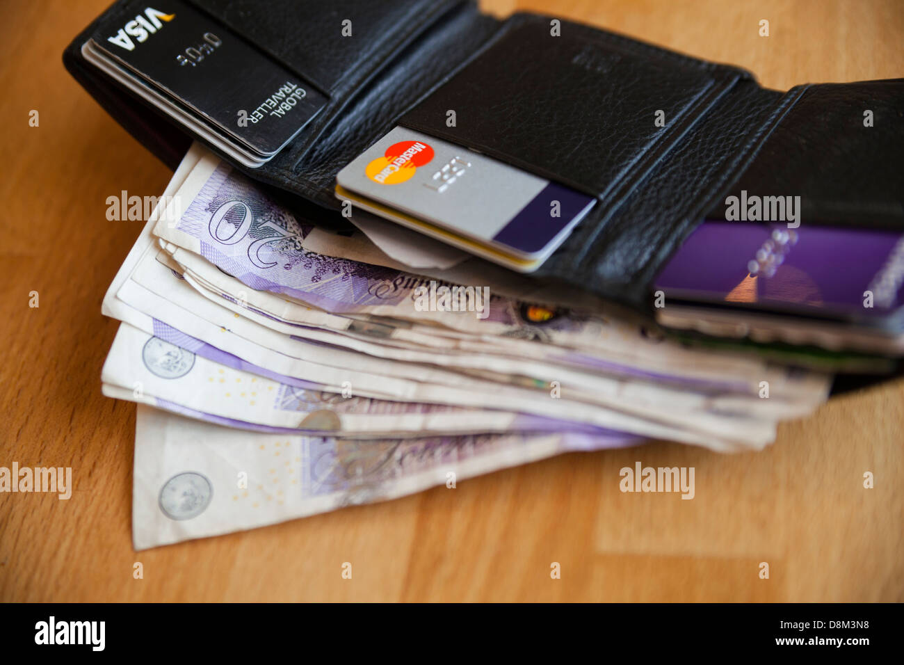 Il portafoglio è pieno di venti pound note su una tavola di legno Foto Stock