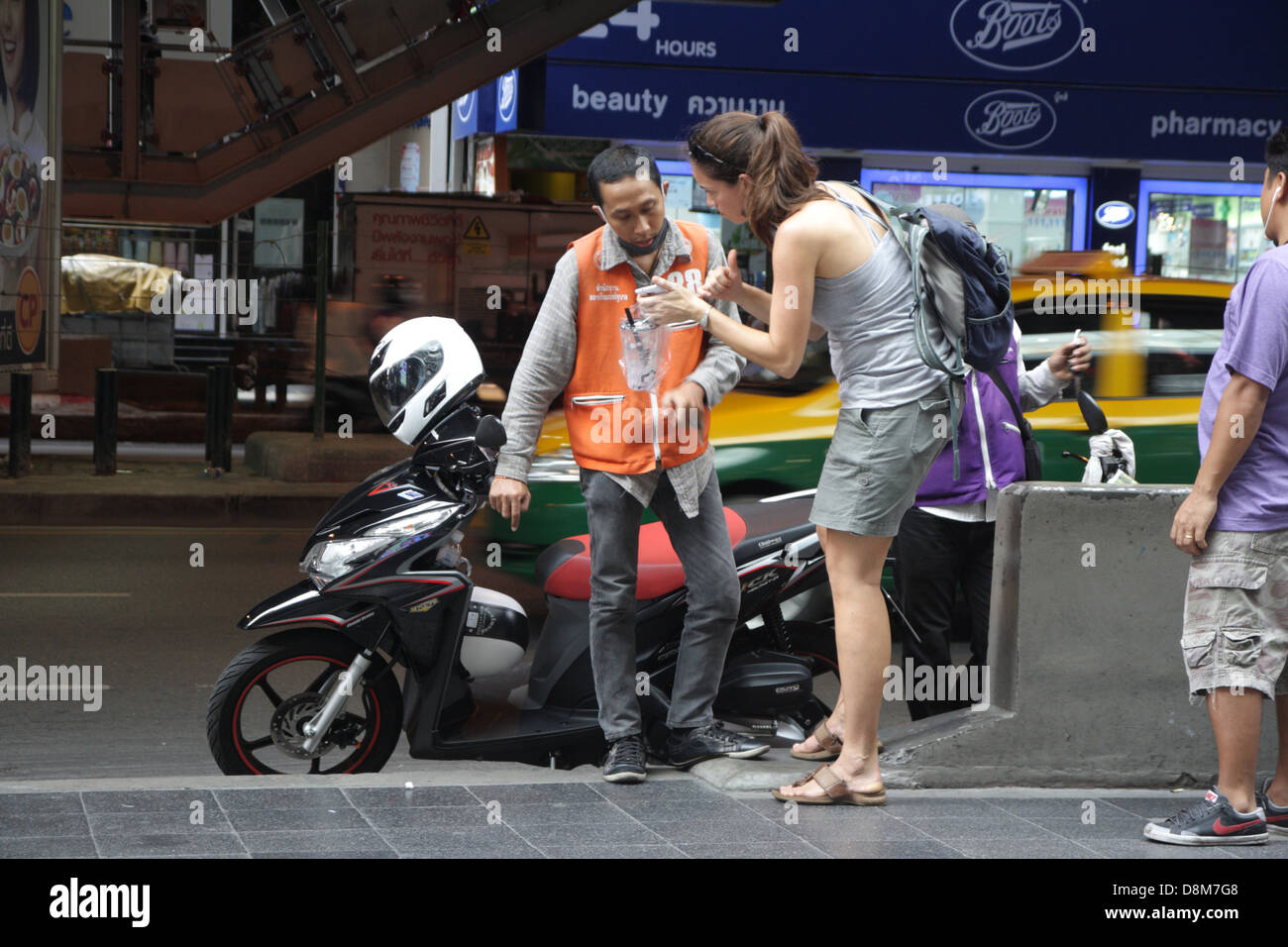I turisti stranieri a parlare con Thai motociclo taxi su Silom Road di Bangkok , Thailandia Foto Stock