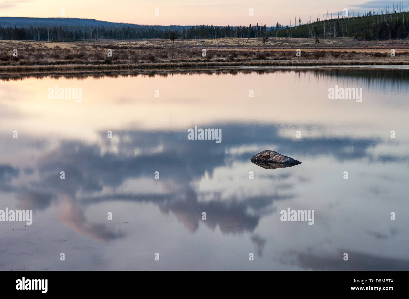 Una roccia si trova in mezzo a un riflesso sunrise in Swan Lake nel nord del Parco Nazionale di Yellowstone. Foto Stock