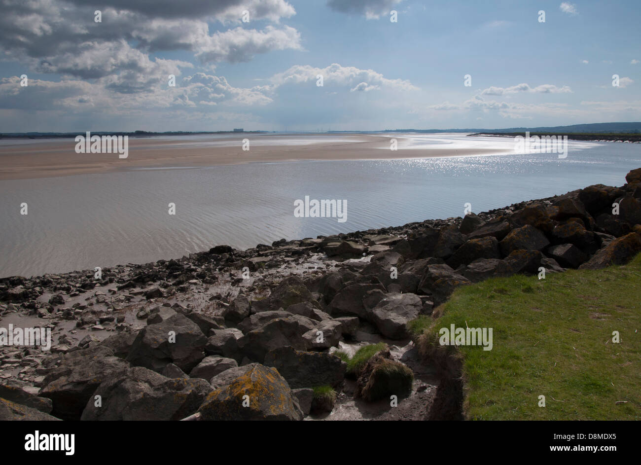 Fiume Severn, le misure di difesa contro le inondazioni, rocce e massi sparsi,banca d'erba, fango, lichen, skyscape, cielo blu, bianco e grigio nuvole Foto Stock