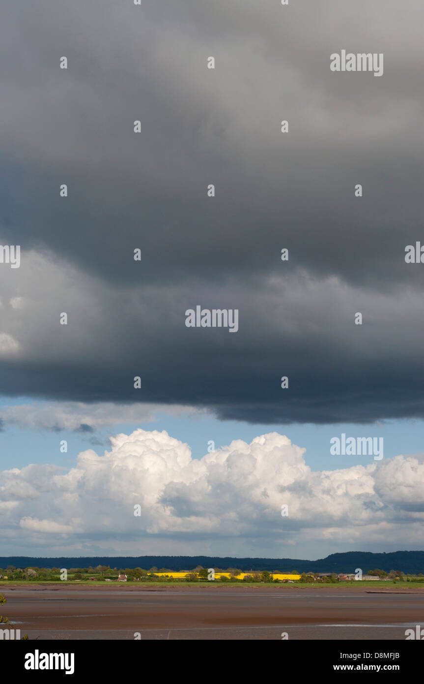 Fiume Severn, le misure di difesa contro le inondazioni, rocce e massi sparsi,banca d'erba, fango, lichen, skyscape, cielo blu, bianco e grigio nuvole Foto Stock