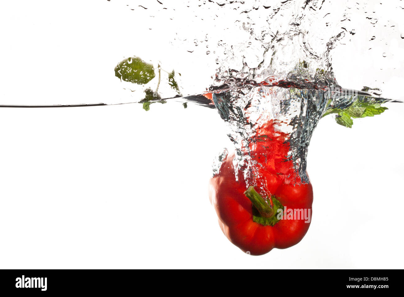 Peperone rosso in acqua con spruzzi su sfondo bianco, orizzontale Foto Stock