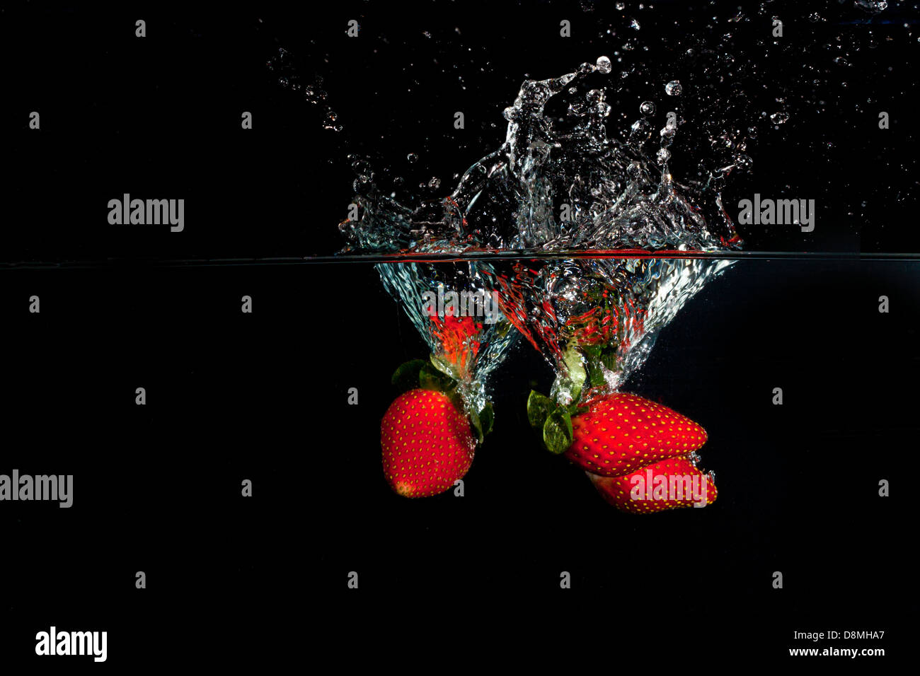 Le fragole in acqua con schizzi su sfondo nero, orizzontale Foto Stock