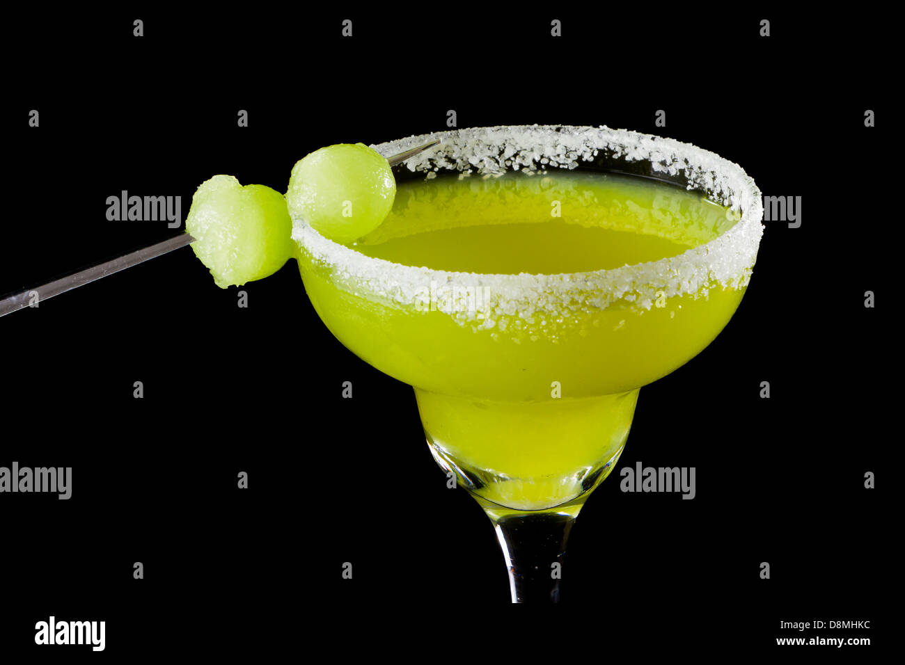 Colore verde brillante margarita servita con sale sul bordo e mellon sfere isolate su uno sfondo nero Foto Stock