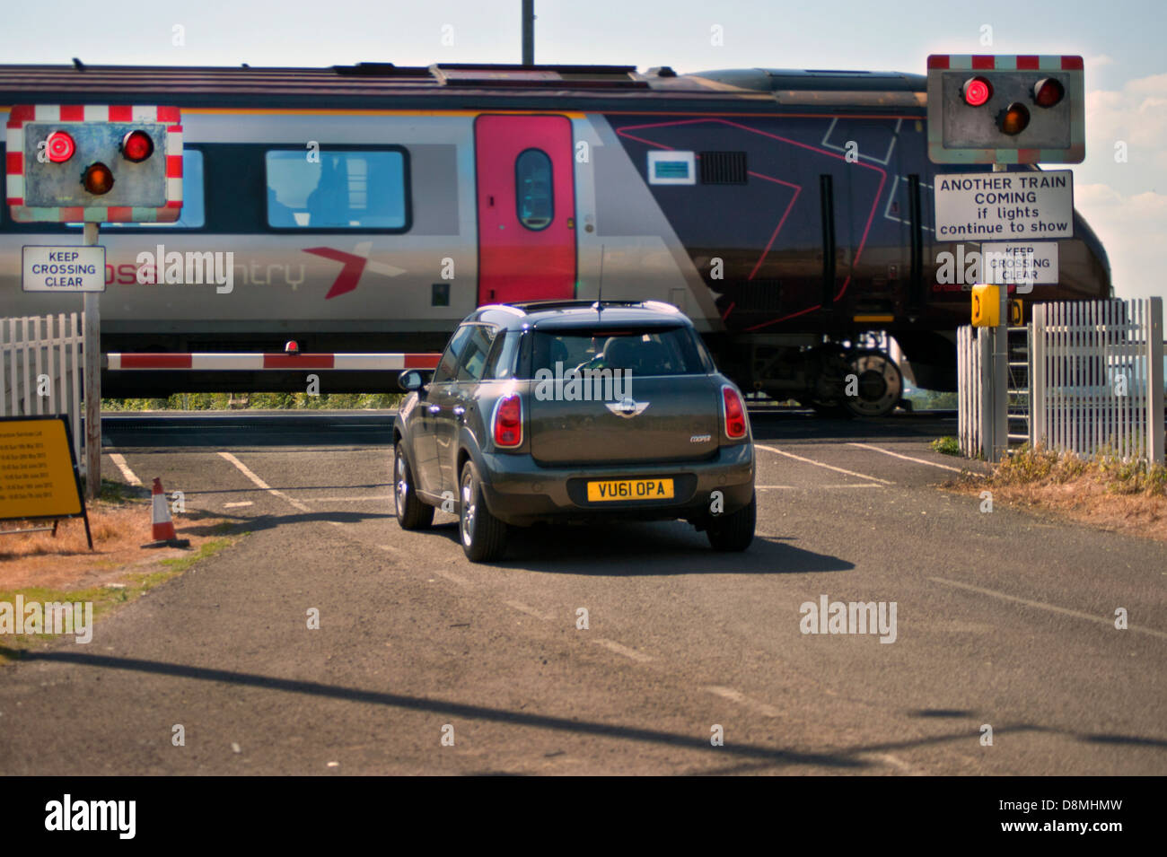 Auto in attesa al passaggio a livello mentre il treno passa Foto Stock