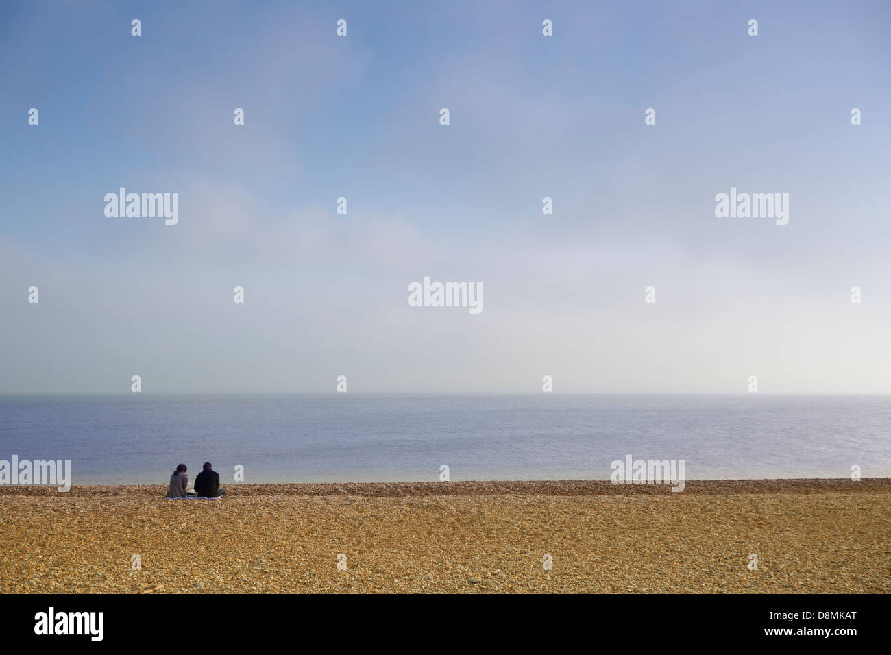 Due persone che guardano al mare, seduto sulla sabbia. Foto Stock