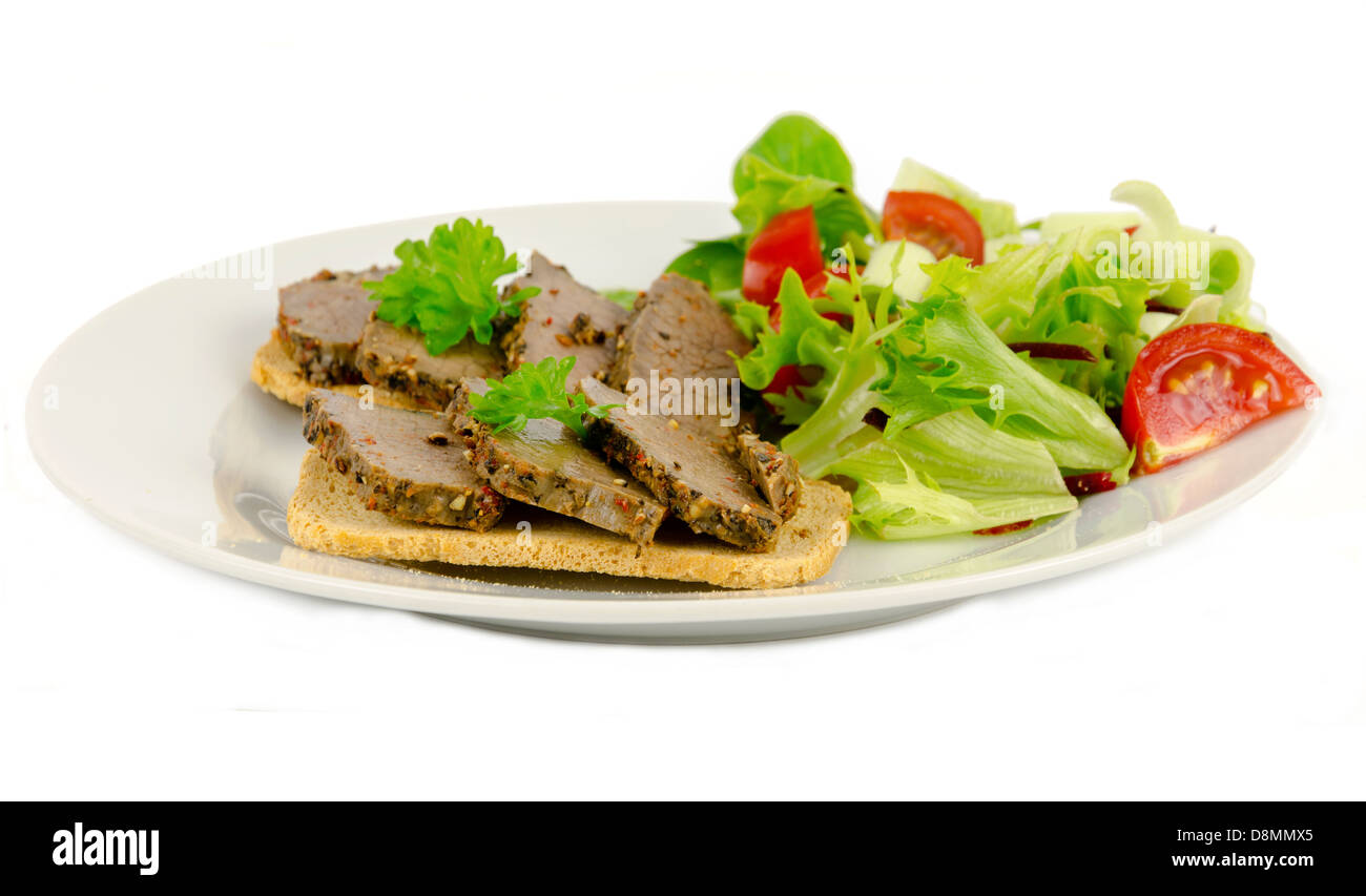 Fette di bistecca di peppe servita sulla sommità di Melba toast su uno sfondo bianco. Foto Stock