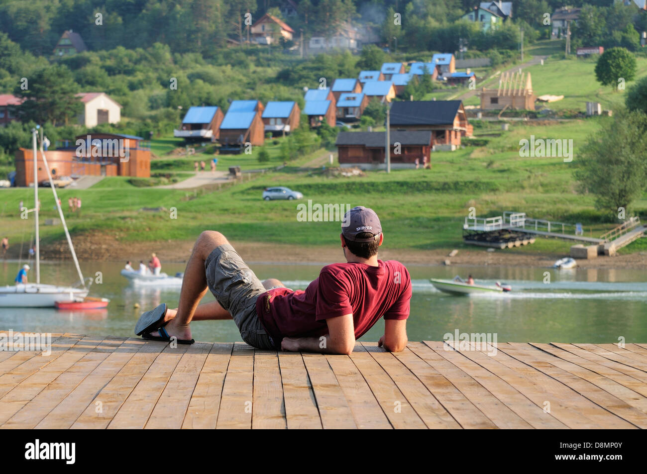 Uomo appoggiato su un molo in legno Foto Stock